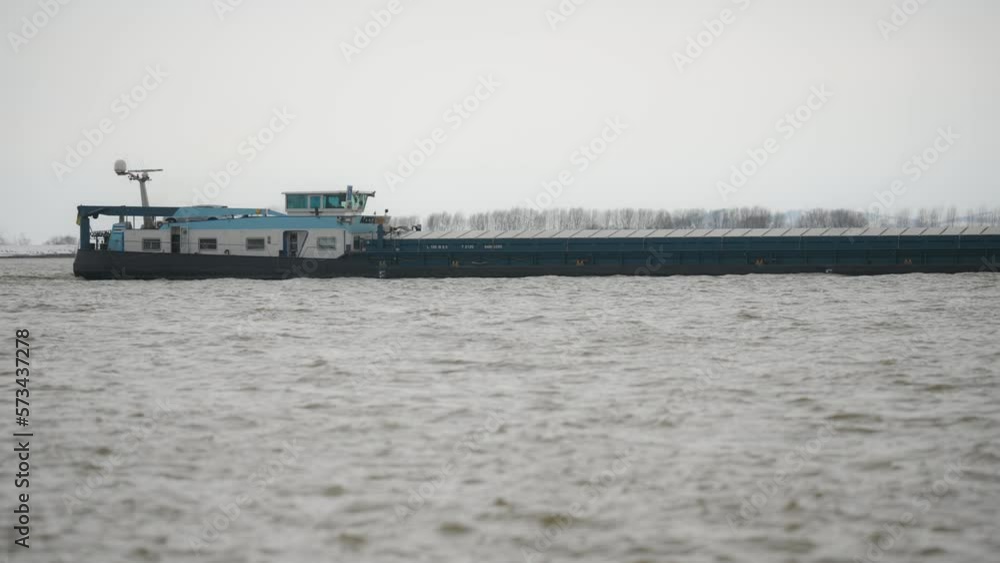 Tracking close up shot with a barge, navigating on a large river, clouded day Tracking close up shot with a barge, navigating on a large river, clouded day