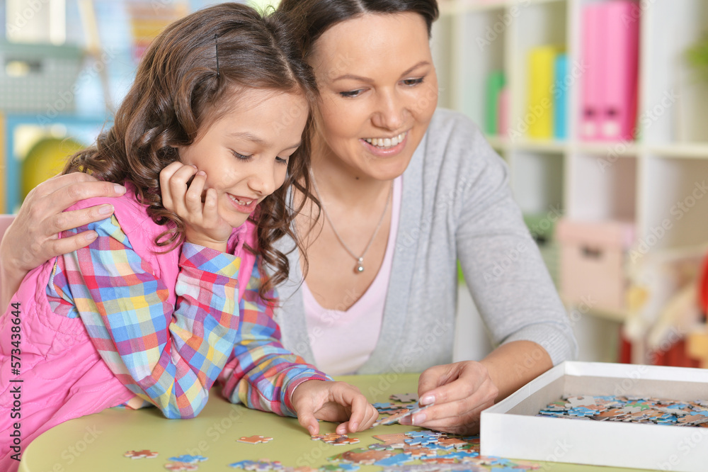 Mother with little daughter collecting puzzle Mother with little daughter collecting puzzle