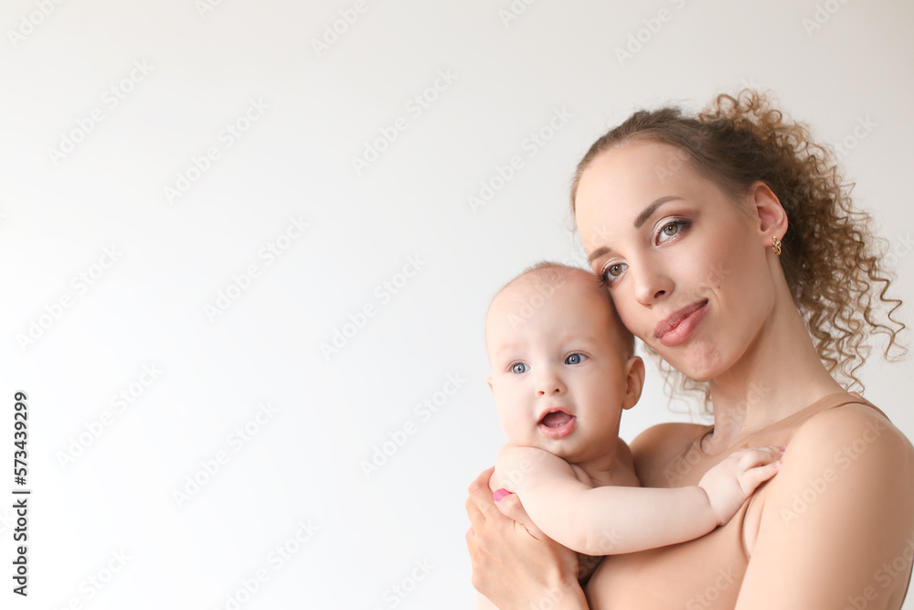 Loving mother hugs and kisses a child, holding him in her arms, in studio on background. Caucasian young woman holding her little son, space for your text Loving mother hugs and kisses a child, holding him in her arms, in studio on background. Caucasian young woman holding her little son, space for your text