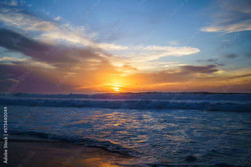 Golden sunset over the sea. Blue waves, bright colorful cloudy sky. Amazing  tranquil scene of empty sand beach