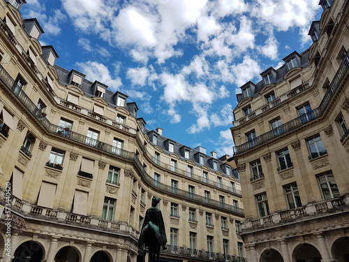 Classic Parisian buildings at Place Edouard VII square from low angle with white clouds on blue sky