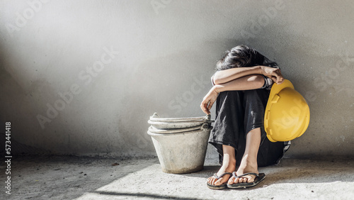 Exhausted little girl sitting on floor concrete wall background. child labor and exploitation