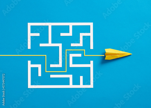 Paper plane breaking through the maze on blue background. photo