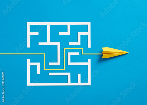 Photos Paper plane breaking through the maze on blue background.