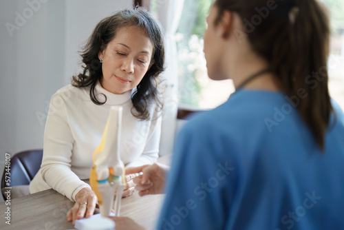 Portrait of a female doctor talking to an elderly patient about osteoarthritis. © Jirapong