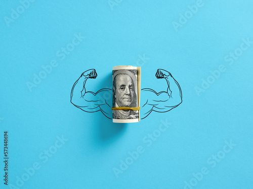 Bunch of United States dollar money with flexing muscle biceps on blue background. Strong or highest currency concept.