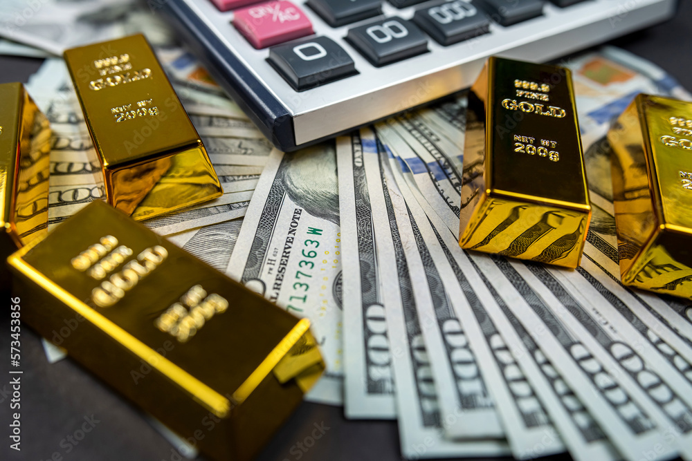 gold bars lie with a calculator near a large sum of dollars isolated. gold bars lie with a calculator near a large sum of dollars isolated.
