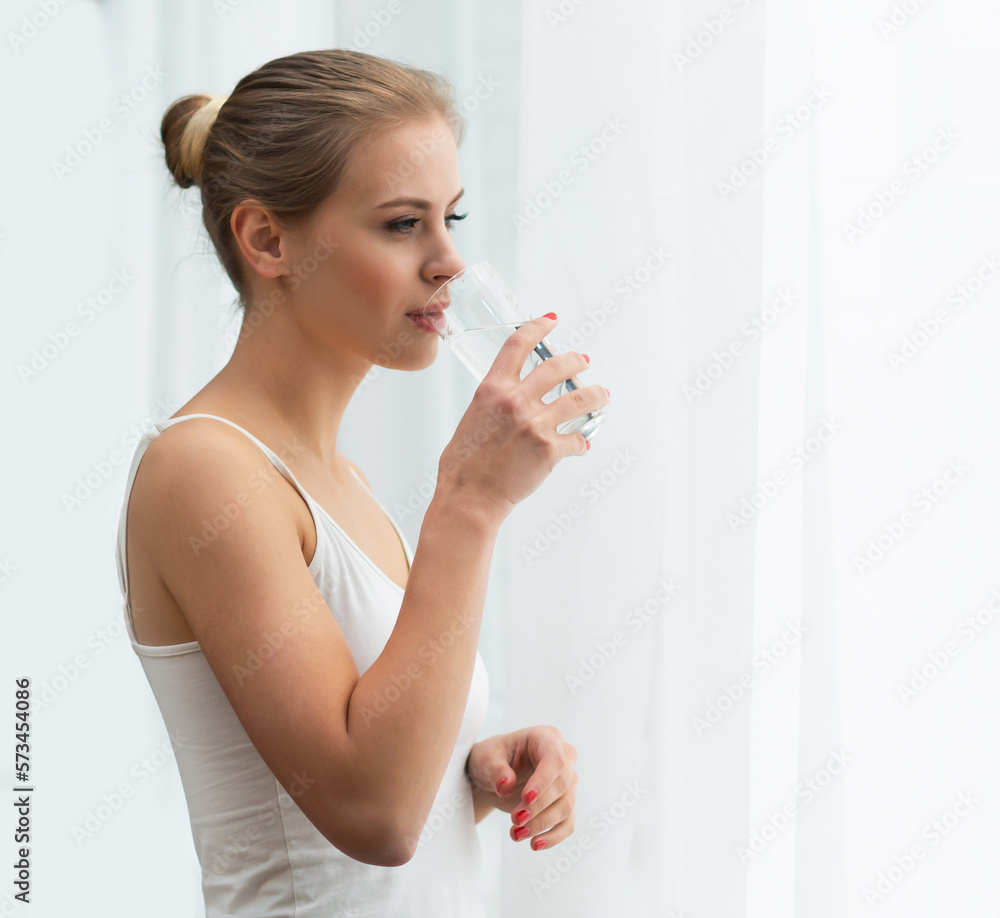 Young woman in white underwear is standing in front of the window and looking into it. Girl at home in the living room. Young woman in white underwear is standing in front of the window and looking into it. Girl at home in the living room.