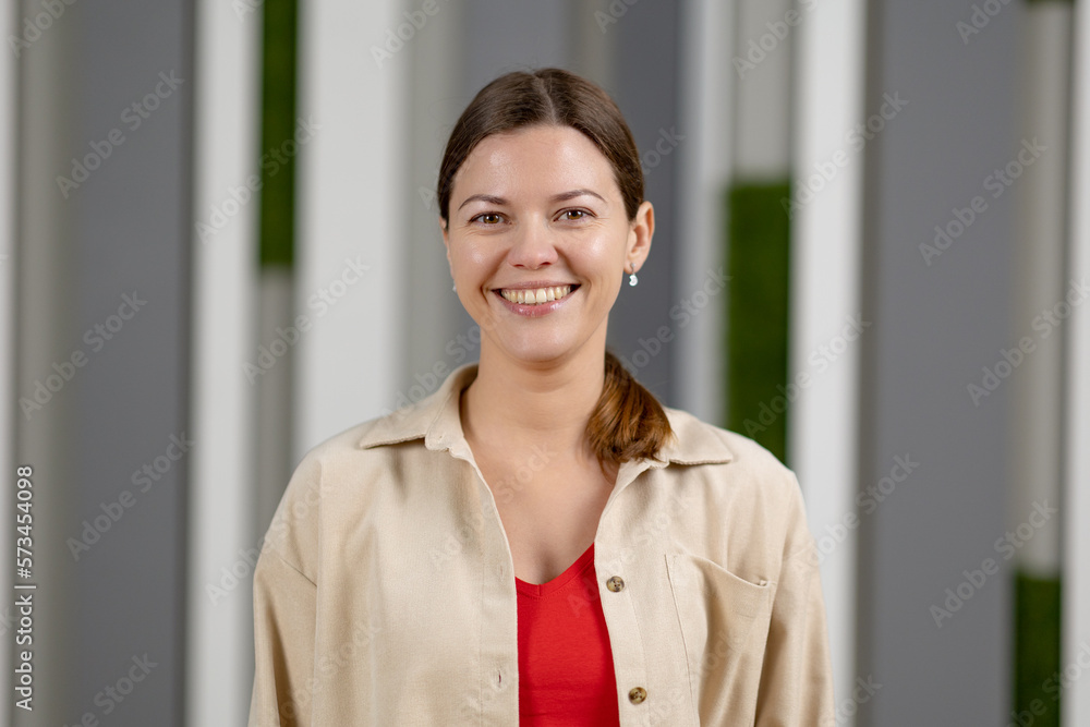 Portrait of young smiling woman looking at camera. Happy girl standing in creative office. Portrait of young smiling woman looking at camera. Happy girl standing in creative office.