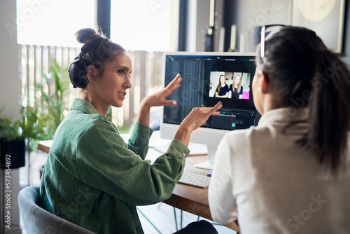 Freelancer explaining colleague over desktop PC at home office photo
