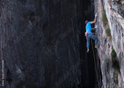 Man with harness climbing rocky mountain