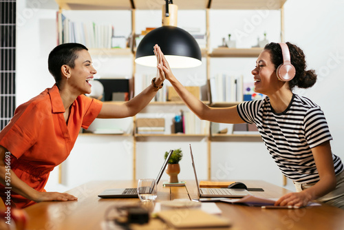 Happy freelancers giving high five at table photo