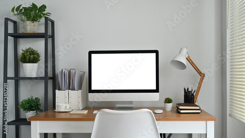 Modern workplace, home office interior with blank computer screen on wooden desk. Empty screen for your advertising design