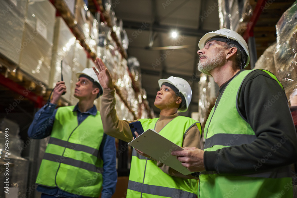 Low angle at group of workers in warehouse doing stock review and storage management