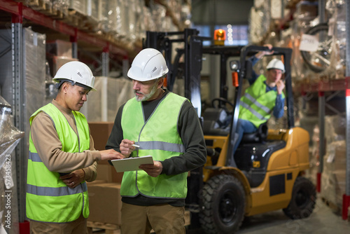Waist up portrait of two workers doing inspection in warehouse and holding clipboard, copy space