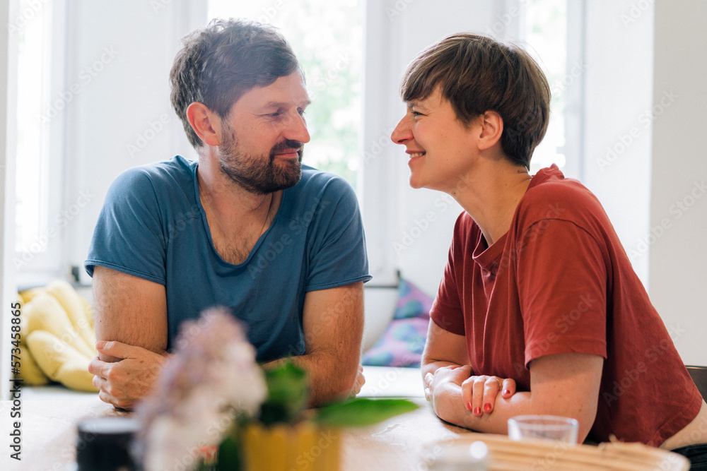 Romantic couple looking at each other sitting in home Romantic couple looking at each other sitting in home