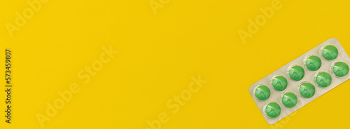 Banner with green pills on a yellow background, advertising medicines, pharmacies, health and treatment concepts © Tetiana Romaniuk