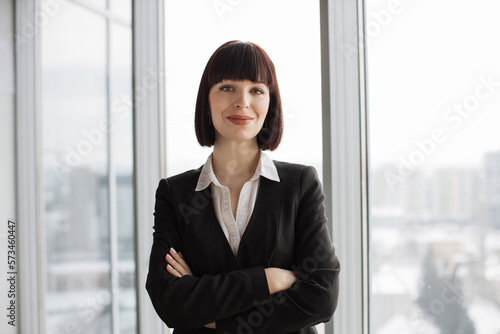 Portrait of a pretty confident red hair business woman in modern office near panoramic window with view of city. Happy business woman in the office interior. Free Download Portrait of a pretty confident red hair business woman in modern office near panoramic window with view of city. Happy business woman in the office interior. - GFXLoad