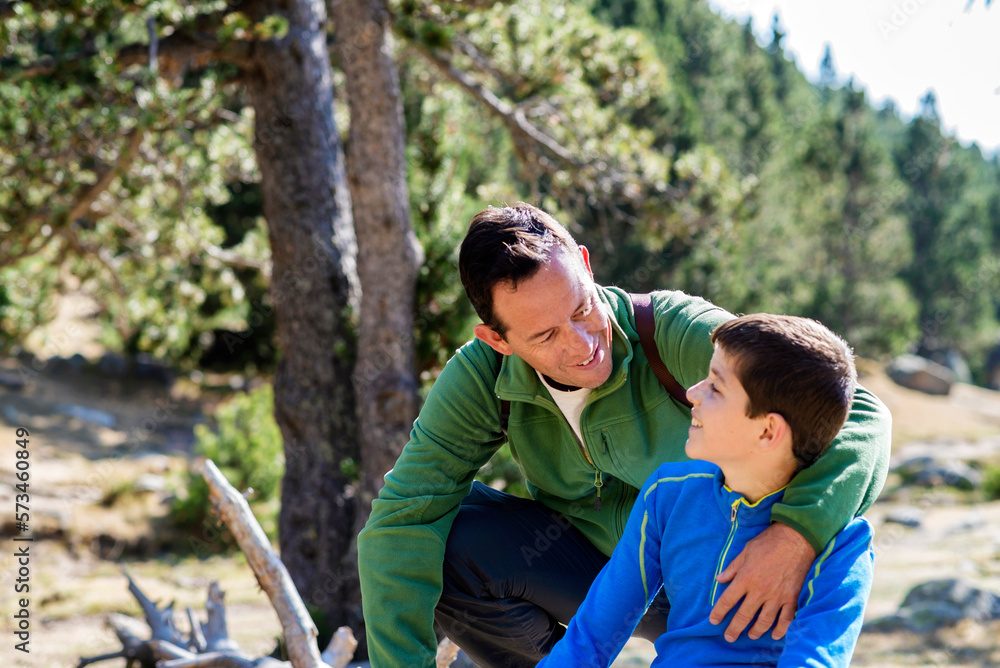 Low angle view of father & son hugging in forest, looking each other Low angle view of father & son hugging in forest, looking each other