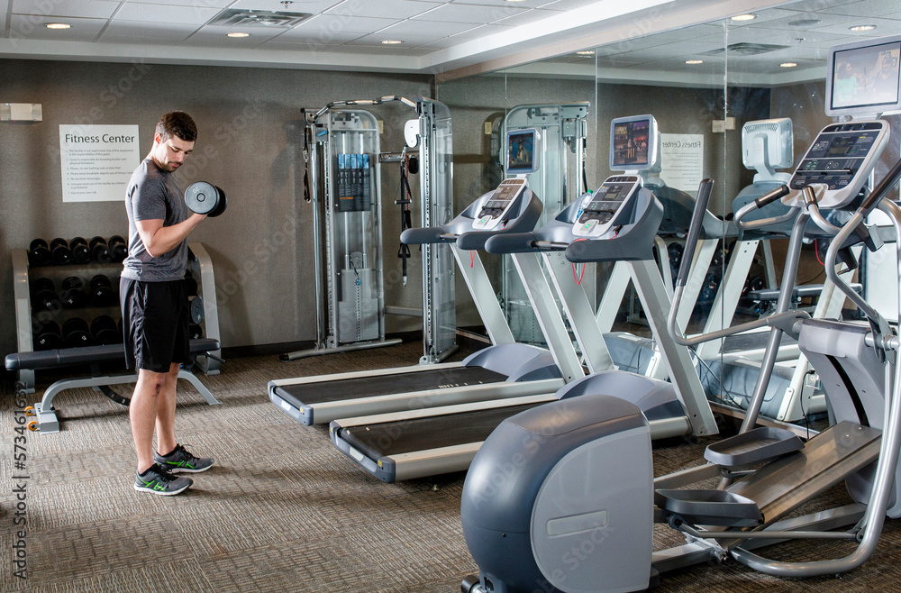 A young man does exercise in a motel gym. A young man does exercise in a motel gym.