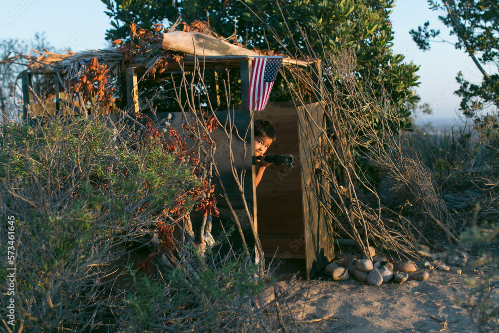 A little boy plays in a jungle inside a deserted soldier outpost, he ...