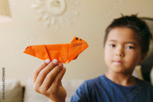 A little boy holds a paper plane made with colourful paper. photo