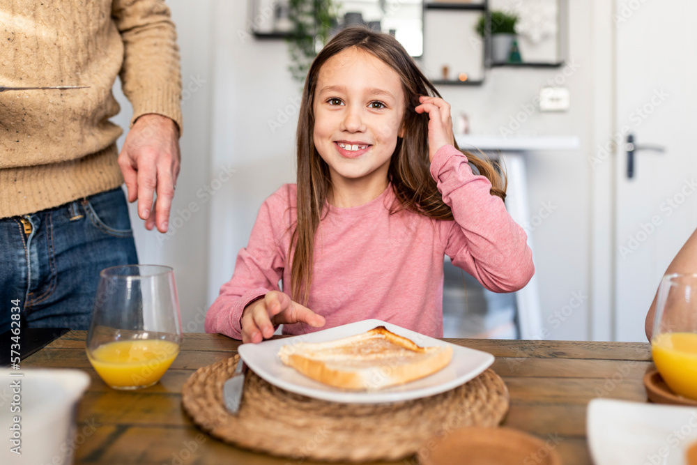 Smiling girl sitting with breakfast at table at home Smiling girl sitting with breakfast at table at home