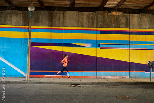 Woman running past underpass mural in Boston, Massachusetts, USA