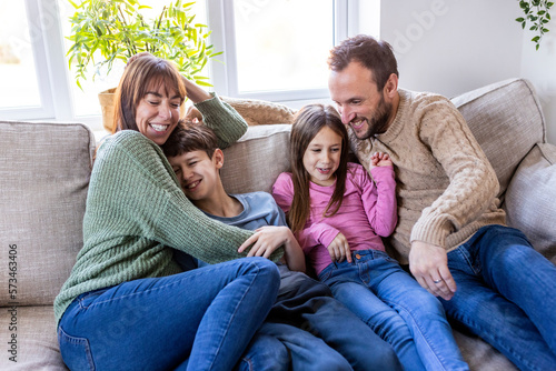 Happy man and woman spending time with children at home