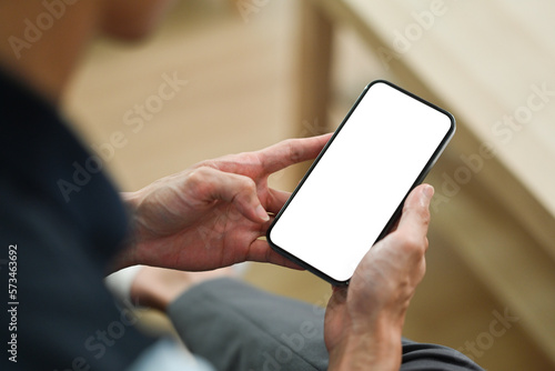 Close up view of man sitting couch and using smart phone. White empty screen for your advertise design