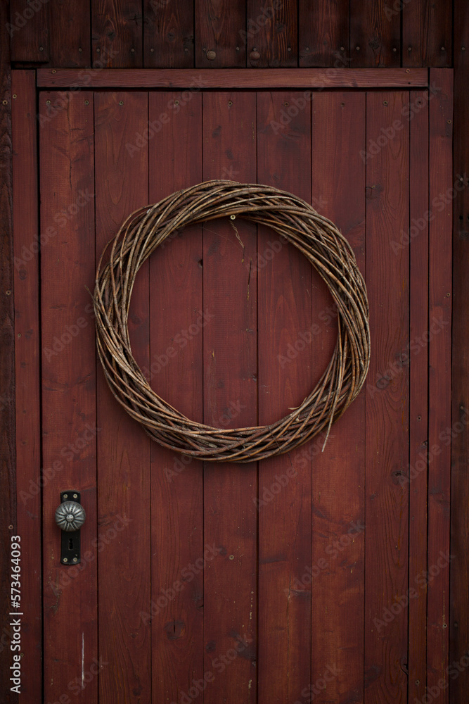 A garland at a red wooden door in a small village. Rhoen Mountains, Germany A garland at a red wooden door in a small village. Rhoen Mountains, Germany