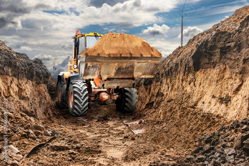 Bulldozer or loader working in the trench. Powerful wheel loader or bulldozer with a large bucket at a construction site. Rental of construction equipment.