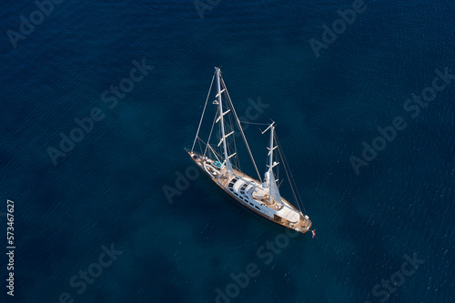 Big wooden sailing yacht on dark water aerial view. Mega sailing yacht in the sea at the anchorage top view.