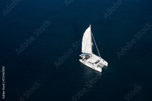 Large white catamaran sailing on dark water top view. © Berg