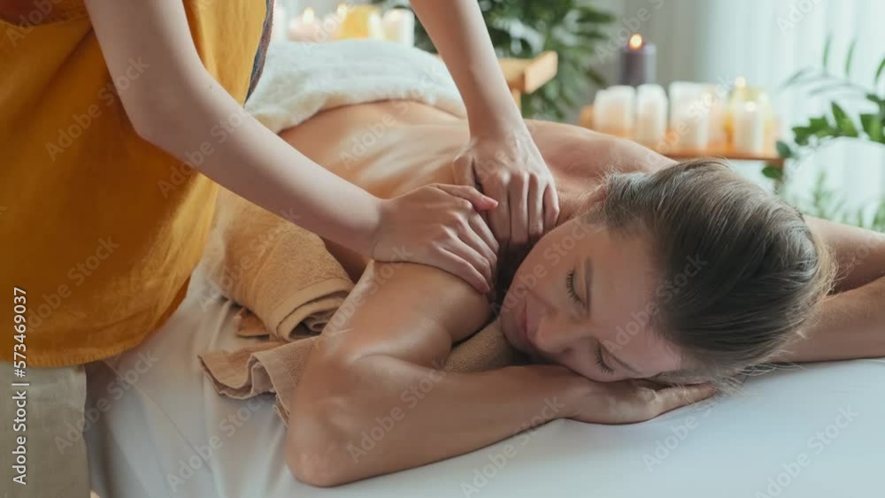 Young beautiful Caucasian woman relaxing during back massage done by Asian masseuse in luxury spa salon Young beautiful Caucasian woman relaxing during back massage done by Asian masseuse in luxury spa salon