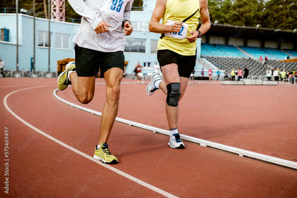 two man athletes run on track stadium marathon race