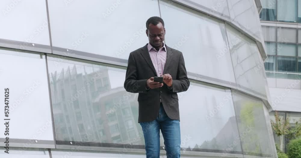 black man walking out the building while seeing his phone feeling painful for heart attack and crouch pressing on his heart black man walking out the building while seeing his phone feeling painful for heart attack and crouch pressing on his heart