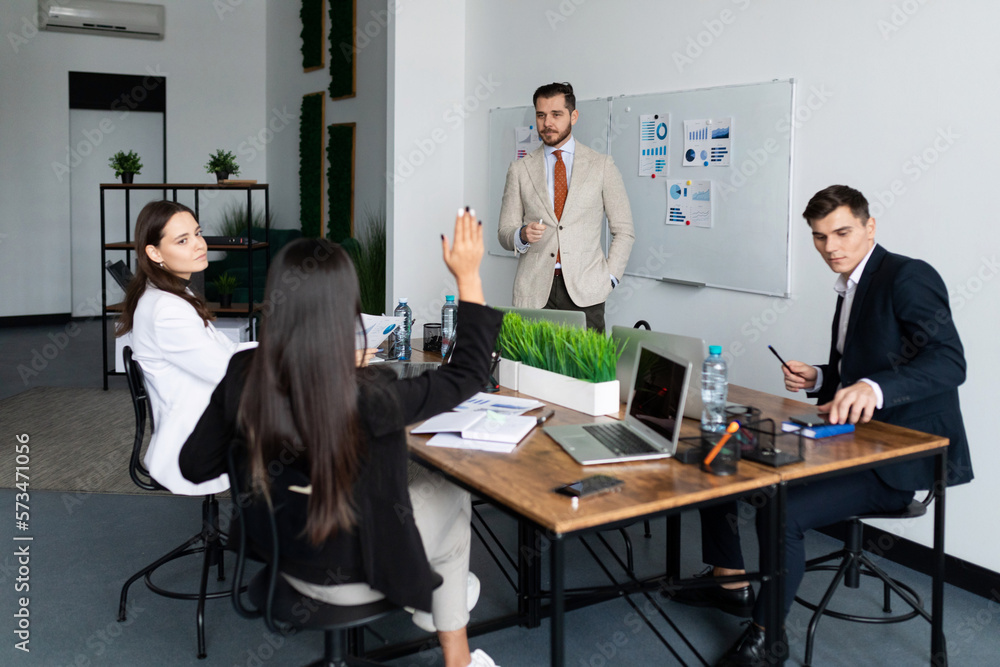 a team of business people discussing business at a large desktop with laptops and documents