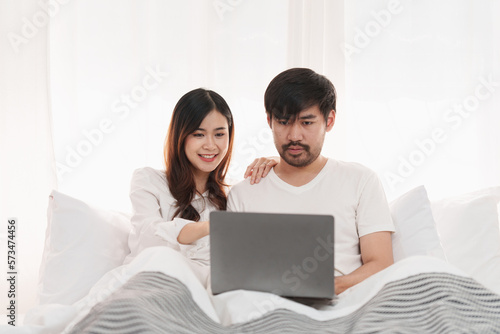 Beautiful asian couple in love and smiling sitting on bed. Romantic moment, relationships, family concept. © itchaznong