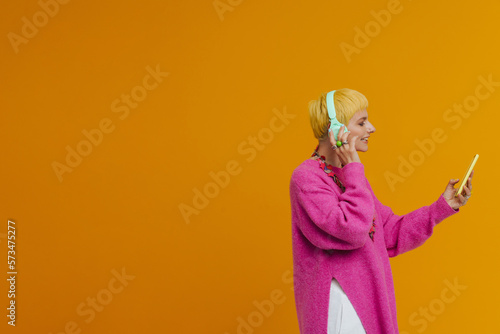 Young short-haired smiling woman in pink sweater using phone