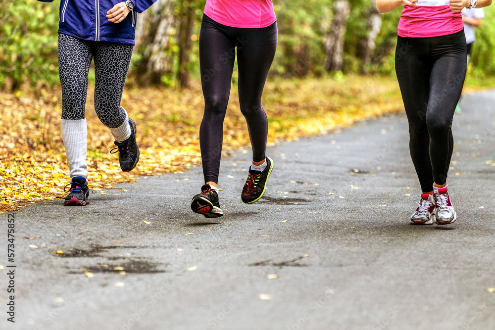 Fototapeta premium legs girls runners in leggings run in autumn Park