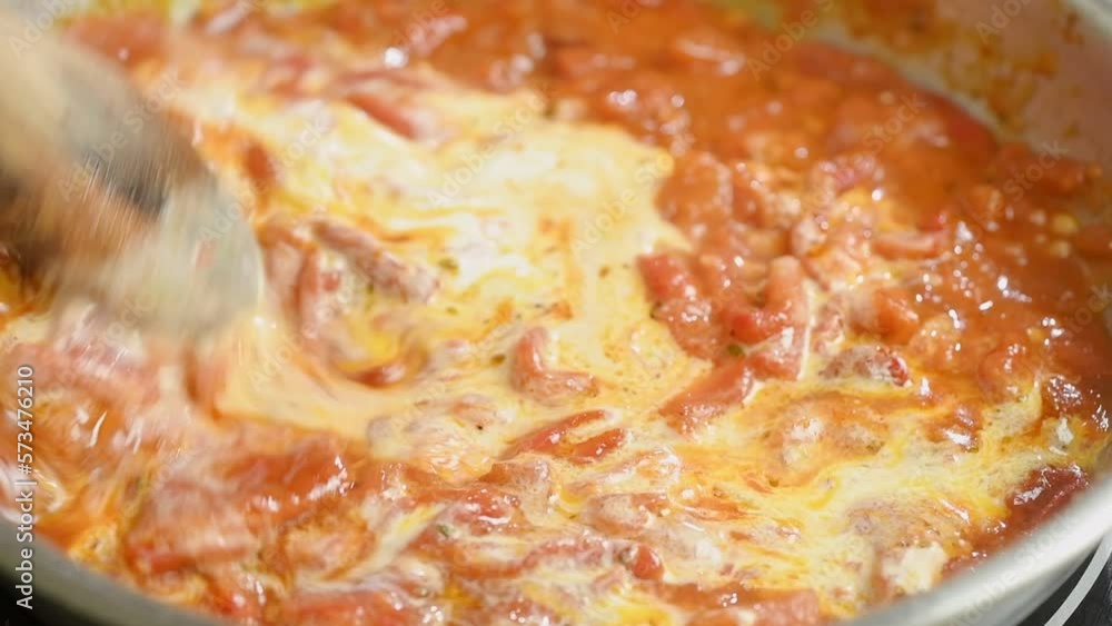 The cook stirs the tomato sauce with heavy cream in the frying pan with a wooden spoon.
The cook stirs the tomato sauce with heavy cream in the frying pan with a wooden spoon.