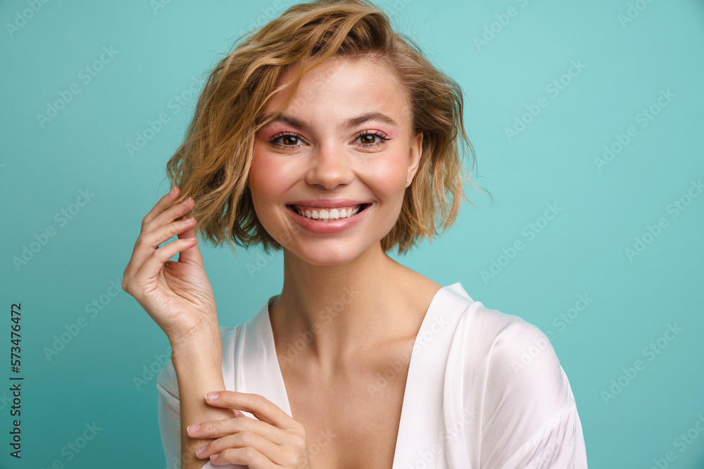 Beautiful woman smiling at camera while posing isolated over blue background Beautiful woman smiling at camera while posing isolated over blue background