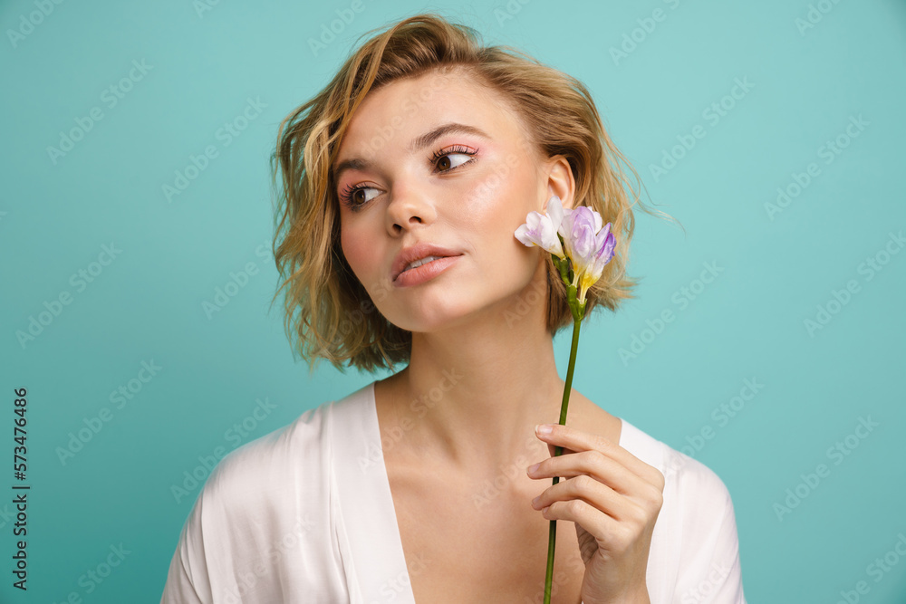 Young beautiful woman posing with freesia flower at her face isolated