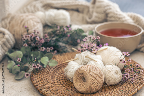 Cozy composition with knitting threads, a cup of tea and flowers.