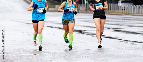Canvas Print three female athletes runners run marathon on wet road