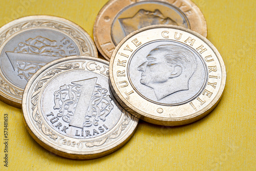 Front and back view of a 1 Turkish Lira Coin on a yellow background.