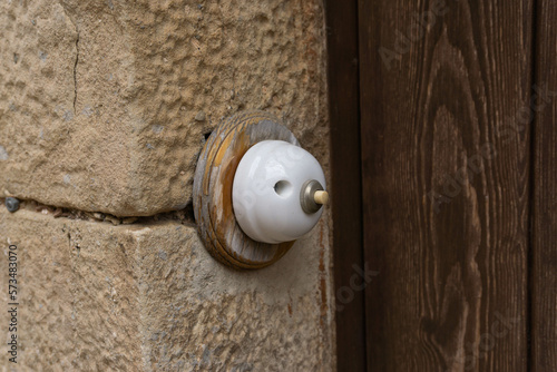 Old doorbell made of plastic and wood on a stone house