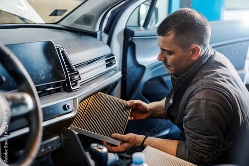 Foto A worker taking out old air filter in car at mechanic's shop.