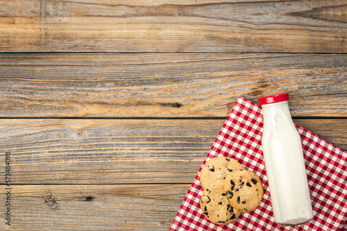 Bottle of milk and cookies on a wooden background, top view.